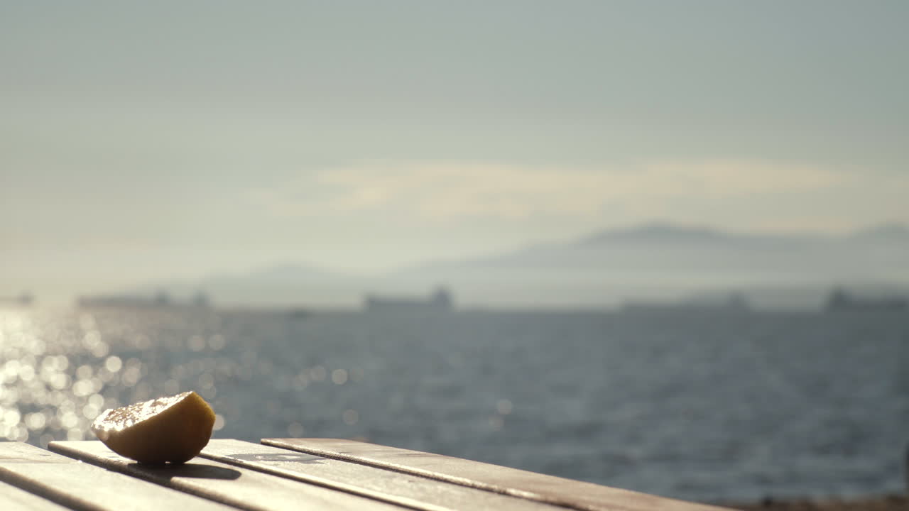바다 배경으로 해변에 있는 나무 테이블 위에 차가운 음료를 놓고 있는 모습