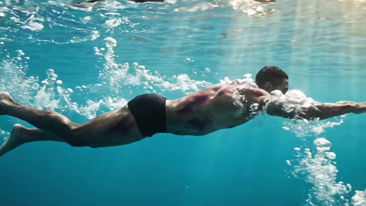 La Elegante Zambullida de un Atleta: Cautivador Viaje Submarino de un Nadador Deslizándose por Aguas Cristalinas con Movimientos Fluidos y la Radiante Luz del Sol Cayendo a Raudales