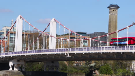 chelsea bridge in london, uk, with a red bus passing on a clear sunny day