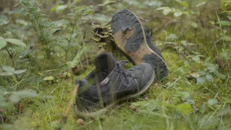 discarded and worn hiking shoes lying in the forest