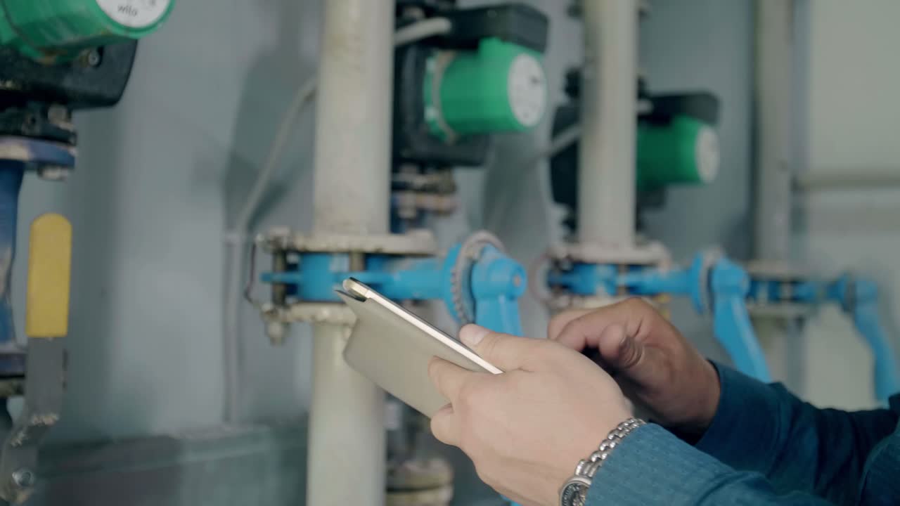 Technician Using Tablet to Monitor Plumbing Equipment