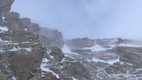 snow dusting over a rocky cliffs during blizzard, in the alps of tyrol, austria - static view