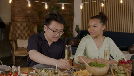 un joven y una chica bonita brindan con sus bebidas antes de una comida