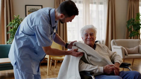 caregiver assisting elderly man in wheelchair at home