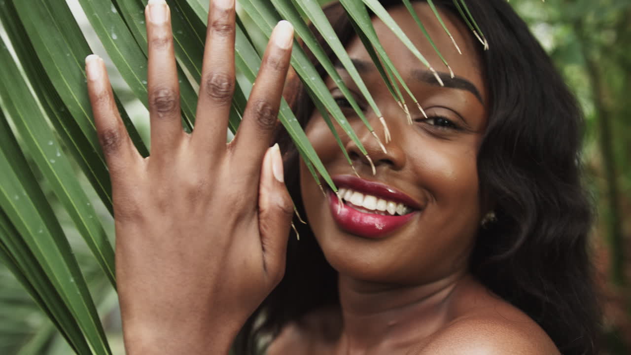 Ritratto di una bellissima ragazza adolescente afroamericana sorridente in spiaggia tropicale mentre guarda la fotocamera