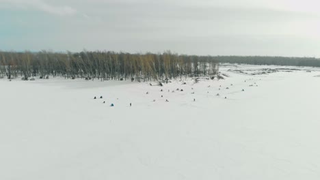fishermen-settle-on-ice-of-white-frozen-river-surface