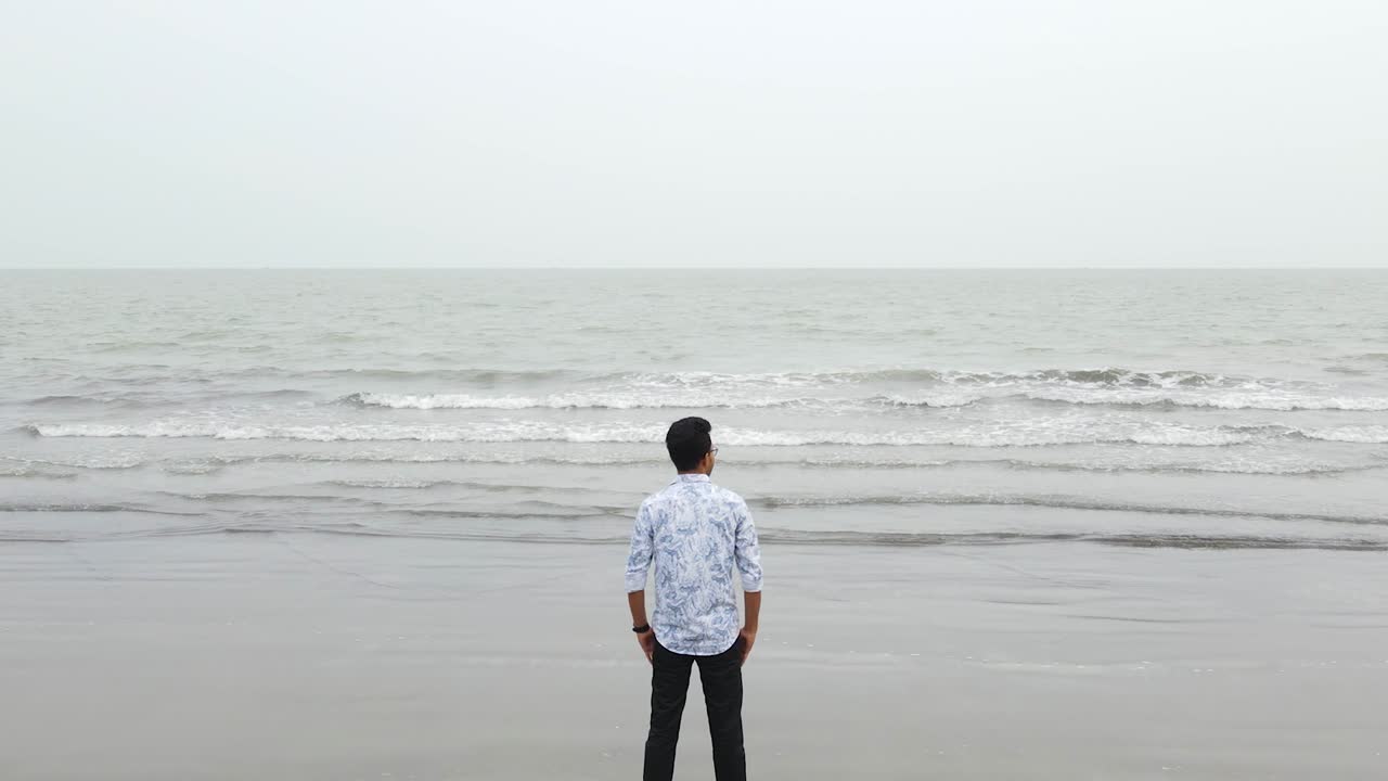 느린 움직임으로 바다를 쳐다보는 외로운 남자의 상승 공중 뷰