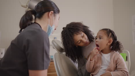 dentista chequeando los dientes de una niña dentro