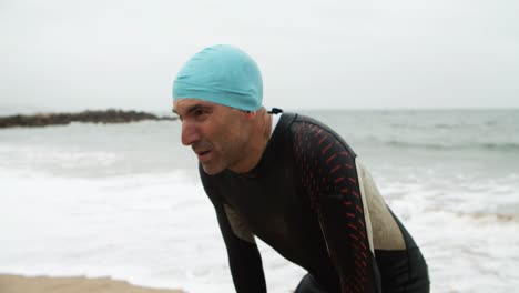 vermoeide mannelijke zwemmer op het strand