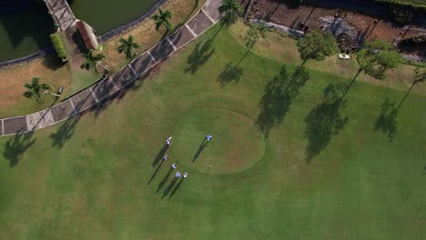 drone shot from above, top to bottom footage shows a golfer taking a tee shot