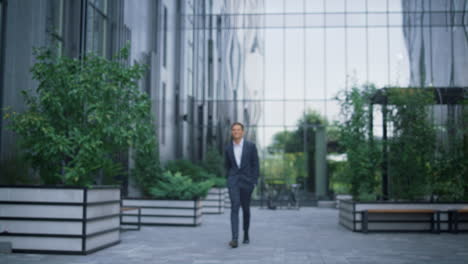attractive businessman walking downtown area alone. modern glass office center