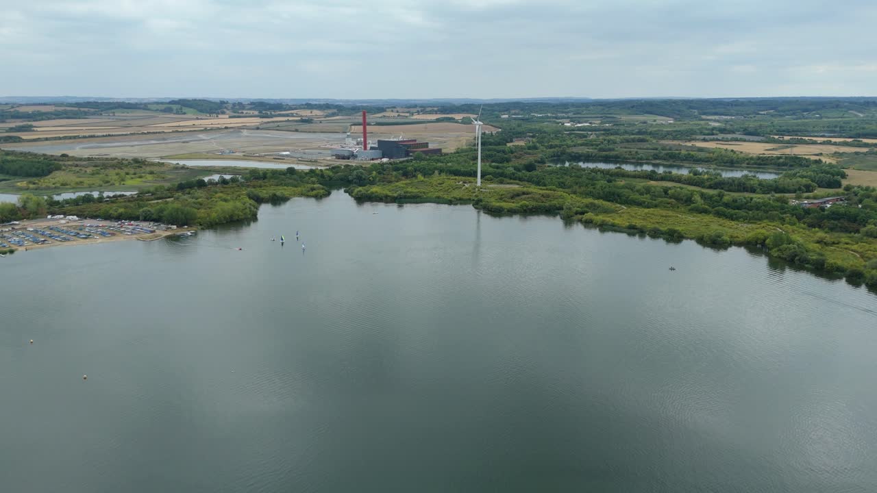Aerial drone video of water sports on large lake with powerboating, sailing, and water skiing surrounded by green trees in Bedford England UK