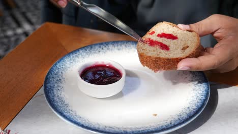 a person spreads jam on bread at a table