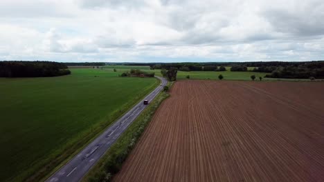 Toma-Aérea-Del-Paisaje-Después-De-Una-Camioneta-Roja-Conduciendo-En-La-Carretera-Zona-Agrícola-Clima-Nublado-Condado-De-Zala-Hungría-Europa