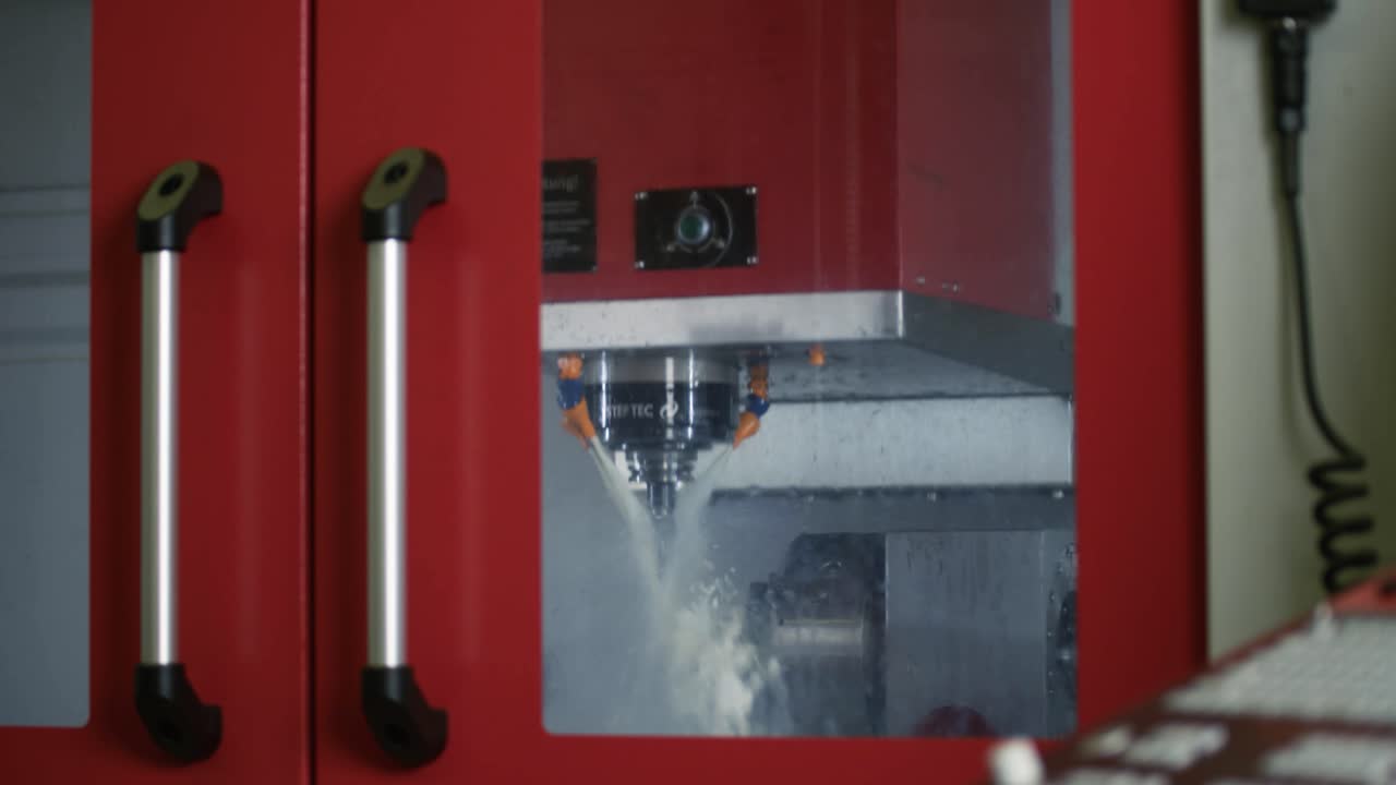 Outside view of a milling machine processing raw metal parts using coolants