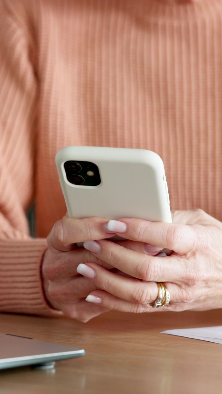Primo piano di una donna che usa lo smartphone alla scrivania