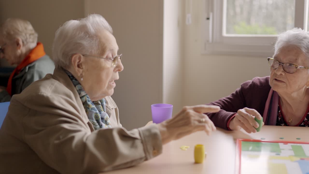 Women having fun playing Parcheesi board game in a geriatric