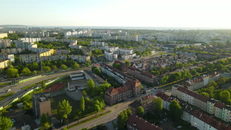 Aerial-view-of-modern-and-old-districts-of-Gdansk-city-in-summer-on-sunrise,-traffic-on-the-speedway-of-Poland,-clean-green-streets-and-city-panorama