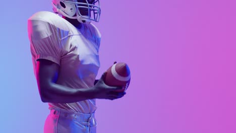 Video-of-african-american-american-football-player-with-copy-space-over-blue-to-pink-neon-background