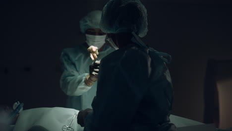 산성 장비를 다루는 간호사 어두운 방 클로즈업. 의료팀 협력