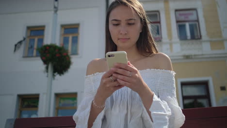 mujer joven enviando mensajes de texto en el teléfono inteligente en la ciudad