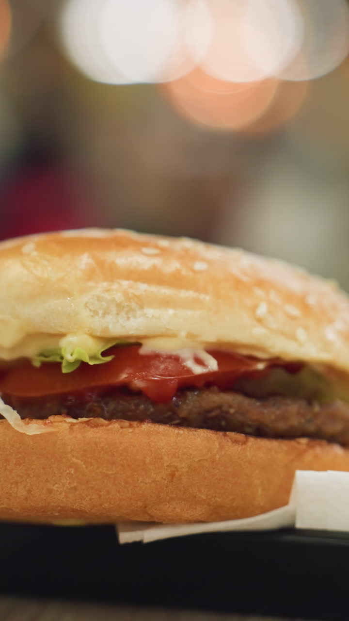 patatas fritas doradas y una hamburguesa en una bandeja negra en una mesa con un fondo borroso de luces, enfatizando la deliciosa comida rápida en un entorno de comedor vibrante
