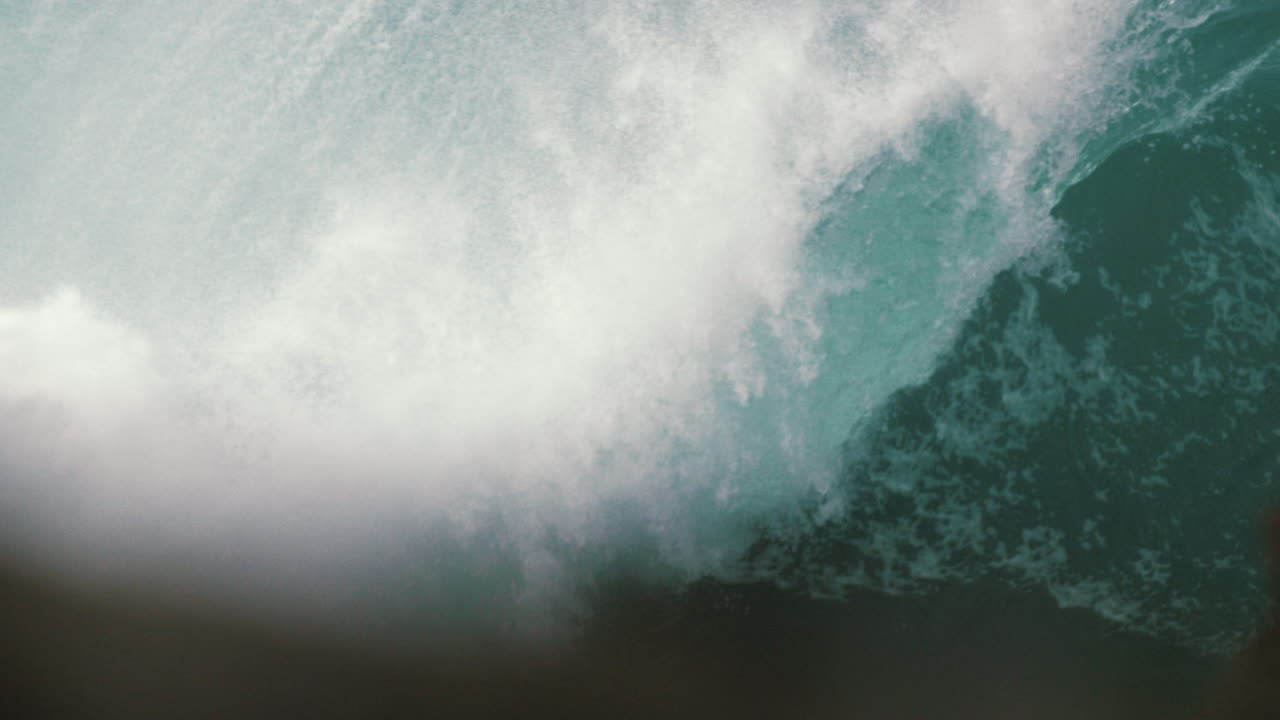 Heavy wave breaking in slow motion behind the rock shelf