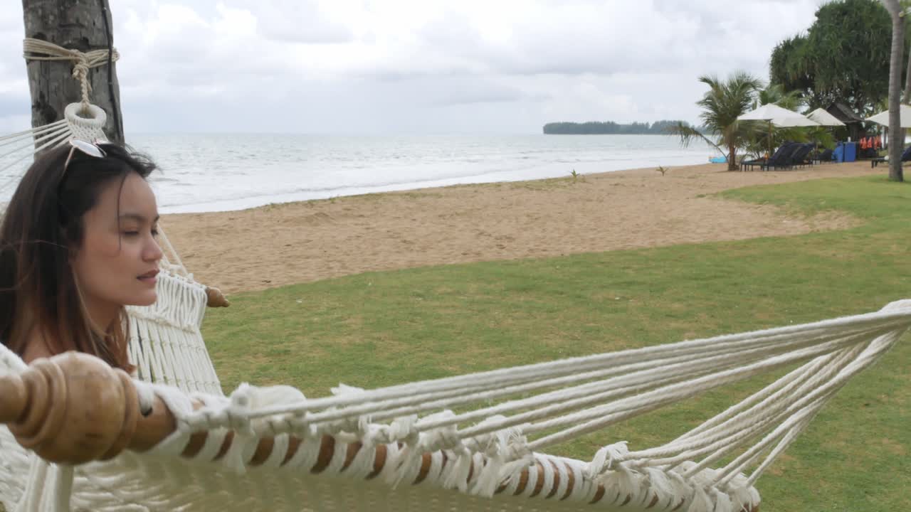 mujer asiática relajándose y en una hamaca cerca de la playa bajo un cocotero en vacaciones-1