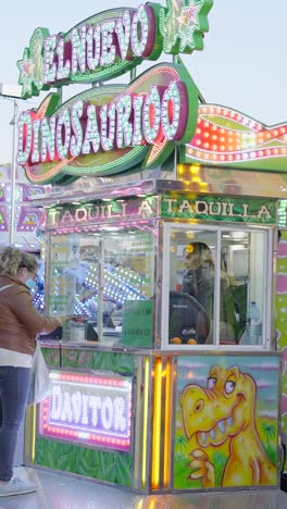 brightly lit dinosaur-themed ride ticket booth at an amusement park