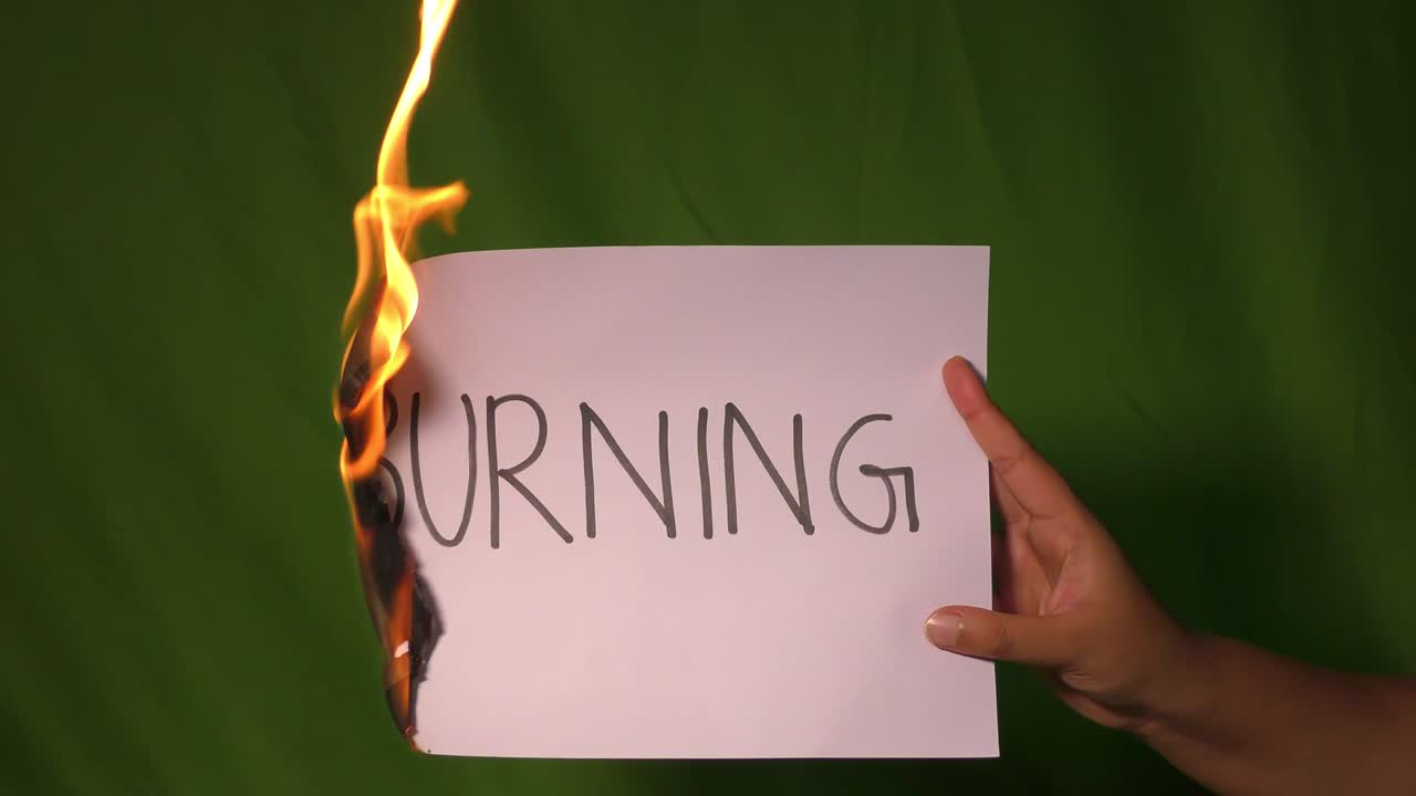 한 손은 불타는 종이를 들고 있고, 그 위에 단줄의 단어가 새겨져 있습니다.