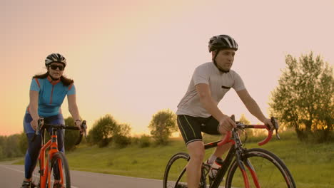 Cyclist-Riding-On-Road-Bike-Rear-View.Cycling-Men-Pedalling-Road-Bicycle-On-City-Park.Tracking-Shot-Of-Cyclist-Rides-On-Road-Bike-At-Sunset-Sun.Cyclist-Athlete-Intensive-Training-On-Bicycle