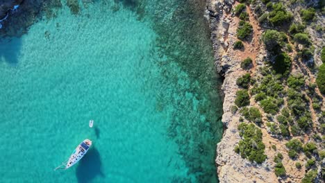 experience the breathtaking beauty of cala varques with its crystal clear waters and rugged cliffs. enjoy a tranquil day with boats gently gliding across the serene ocean, perfect for relaxation.