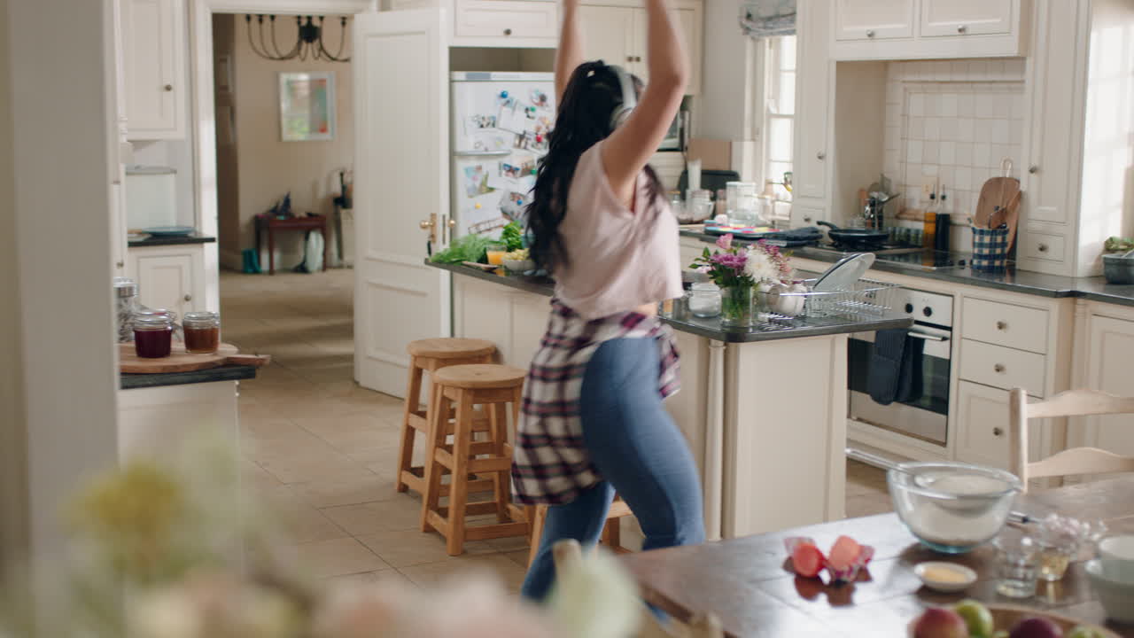 happy overweight teenage girl dancing in kitchen having fun celebrating weekend performing funny dance moves listening to music wearing headphones
