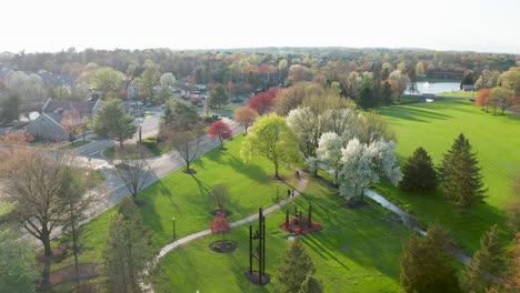 Unrecognizable-couple-walks-dog-on-trail-through-beautiful-nature-park-and-stream-in-suburban-USA