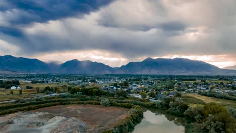 Las-Nubes-Se-Juntan-A-Través-De-Las-Montañas-Del-Valle-Mientras-Los-Rayos-Del-Sol-Estallan-Y-El-Cielo-Se-Refleja-En-El-Agua---Hiperlapso-Aéreo