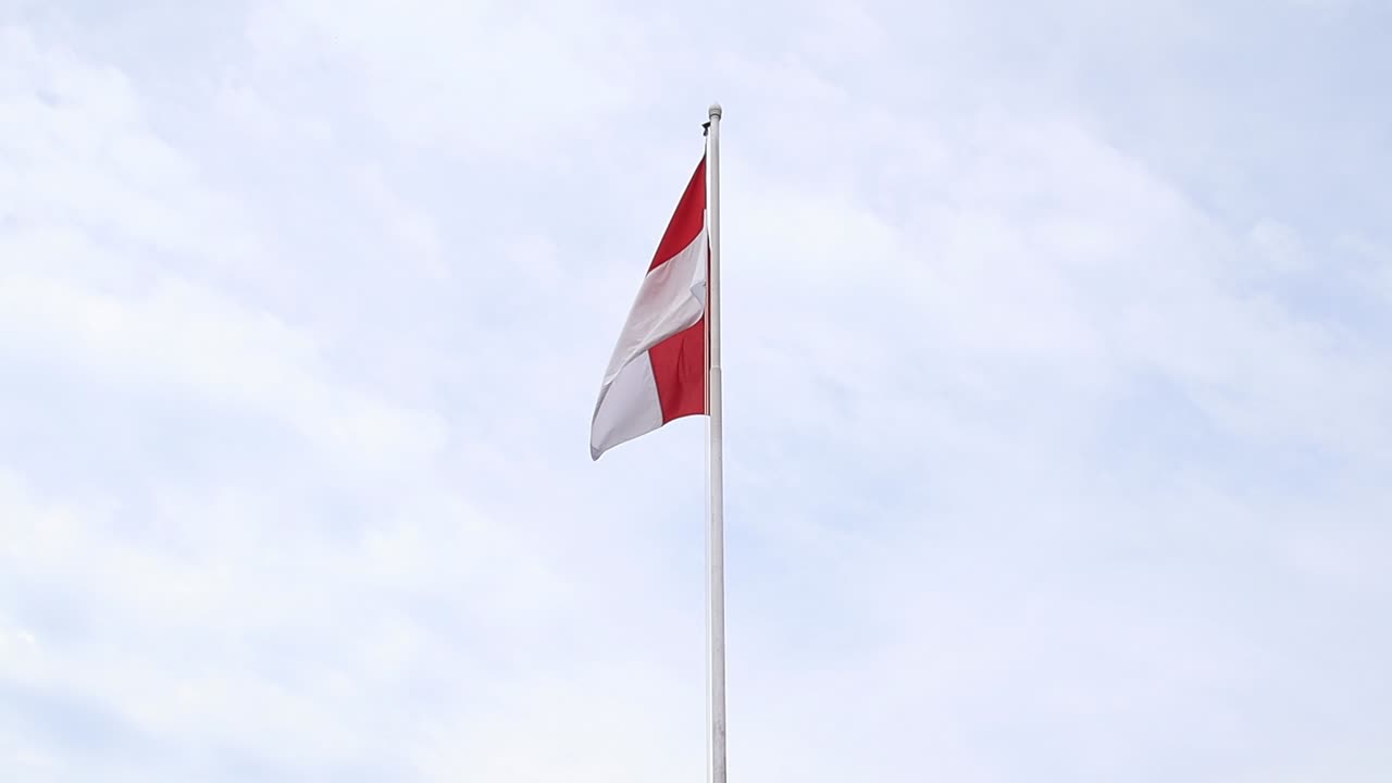 la bandera indonesia roja y blanca fue rasgada, volando en el cielo contra el fondo del cielo azul brillante