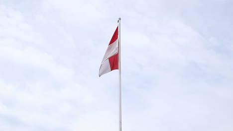 the red and white indonesian flag was torn, flying soaring into the sky against the background of the bright blue sky