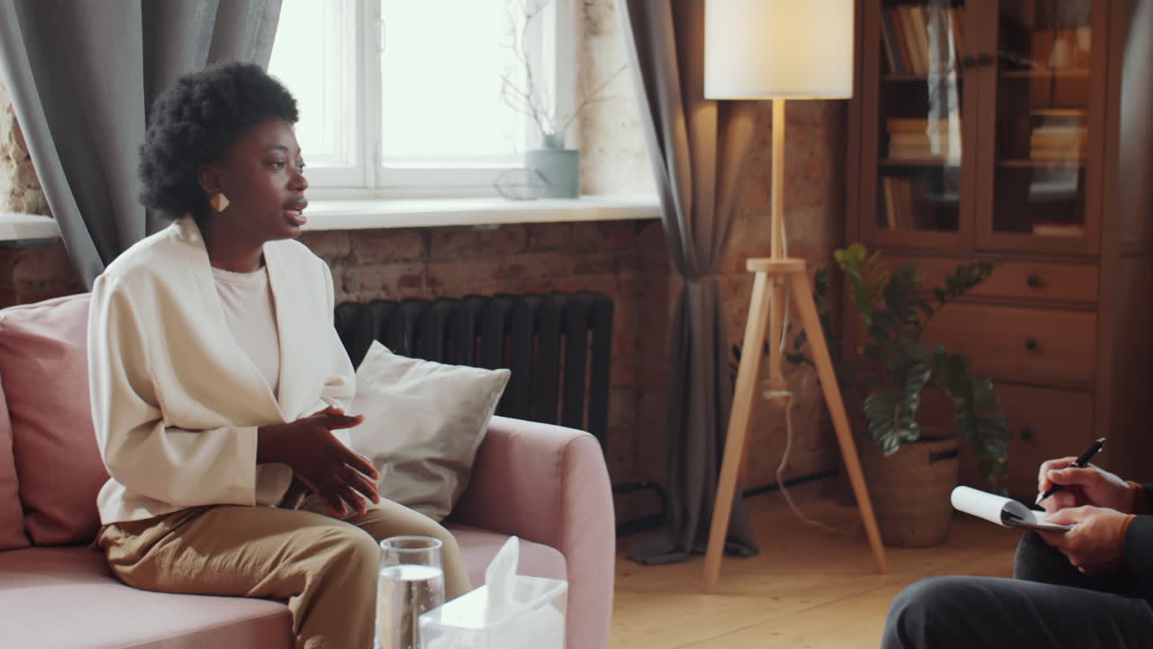 Afroamerikansk kvinde taler med psykolog under en terapisession.