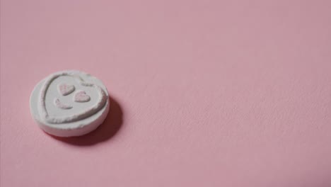 mano recogiendo dulces de corazón con amor romántico emoji sobre fondo rosa