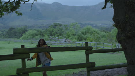 Joven-India-Independiente-Sentada-En-La-Valla-Disfrutando-De-Un-Hermoso-Campo-Verde-Granja-Sonriendo-Alegre-Contemplación-Descansando-Bajo-El-árbol