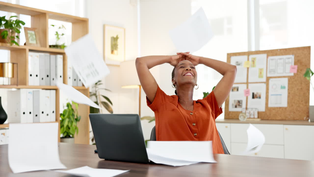 Happy Businesswoman Throws Papers in Air Celebrating Success at Office Desk