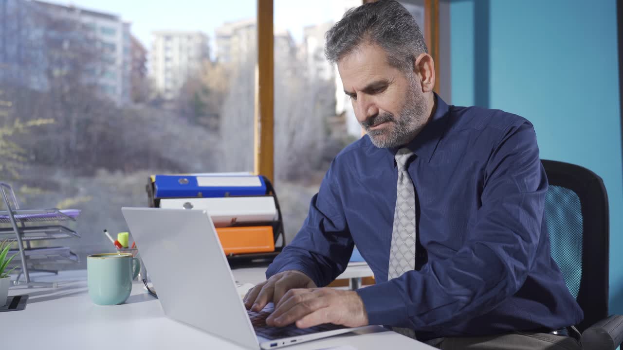 Adult man working in office working on laptop.
