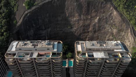 Langsame-Annäherung-Aus-Der-Luft-An-Wohnhochhaus-Eigentumswohnungen,-Die-Sich-In-Einem-Teilweise-Ausgeschnittenen-Berghang-Befinden-Und-Den-Blick-Auf-Die-Dahinter-Liegenden-Pools-Und-Tennisplätze-Freigeben