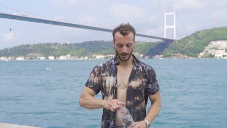 man drinking water by the sea.