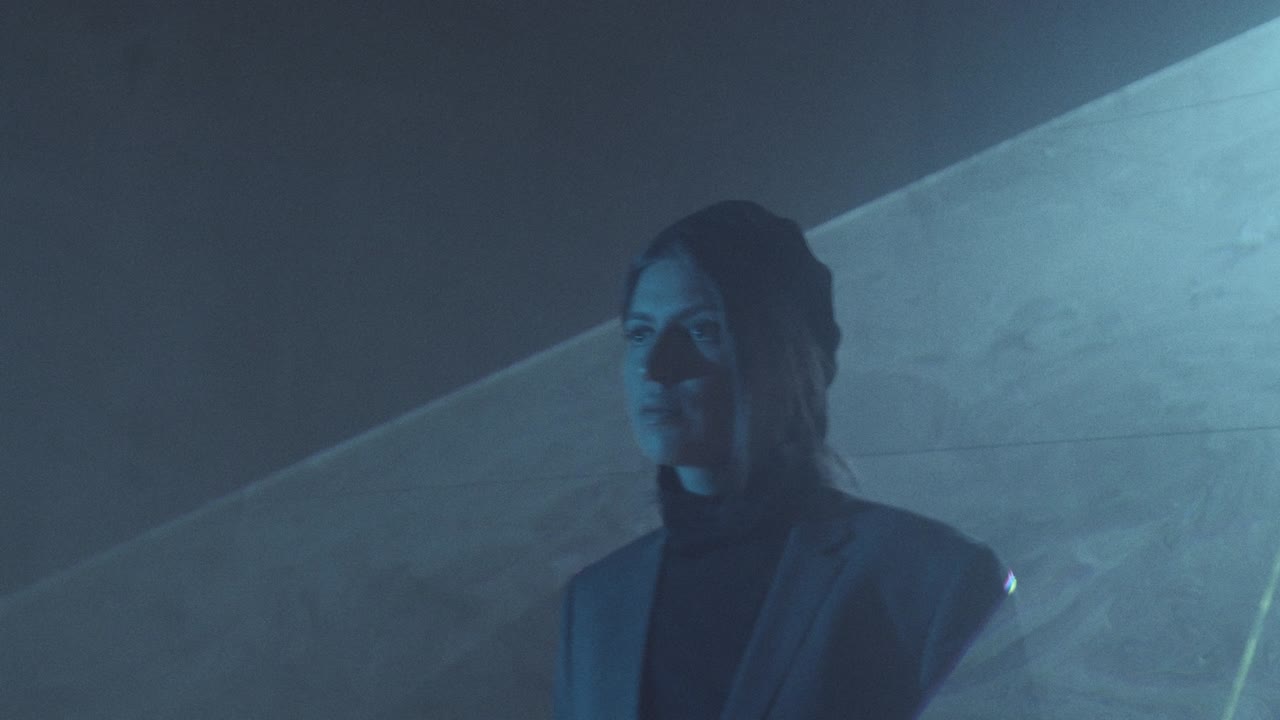 mujer caminando a través de una hoja plana de luz láser en una habitación oscura