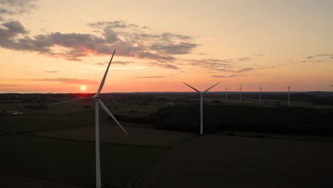 flying behind wind turbines on green fields