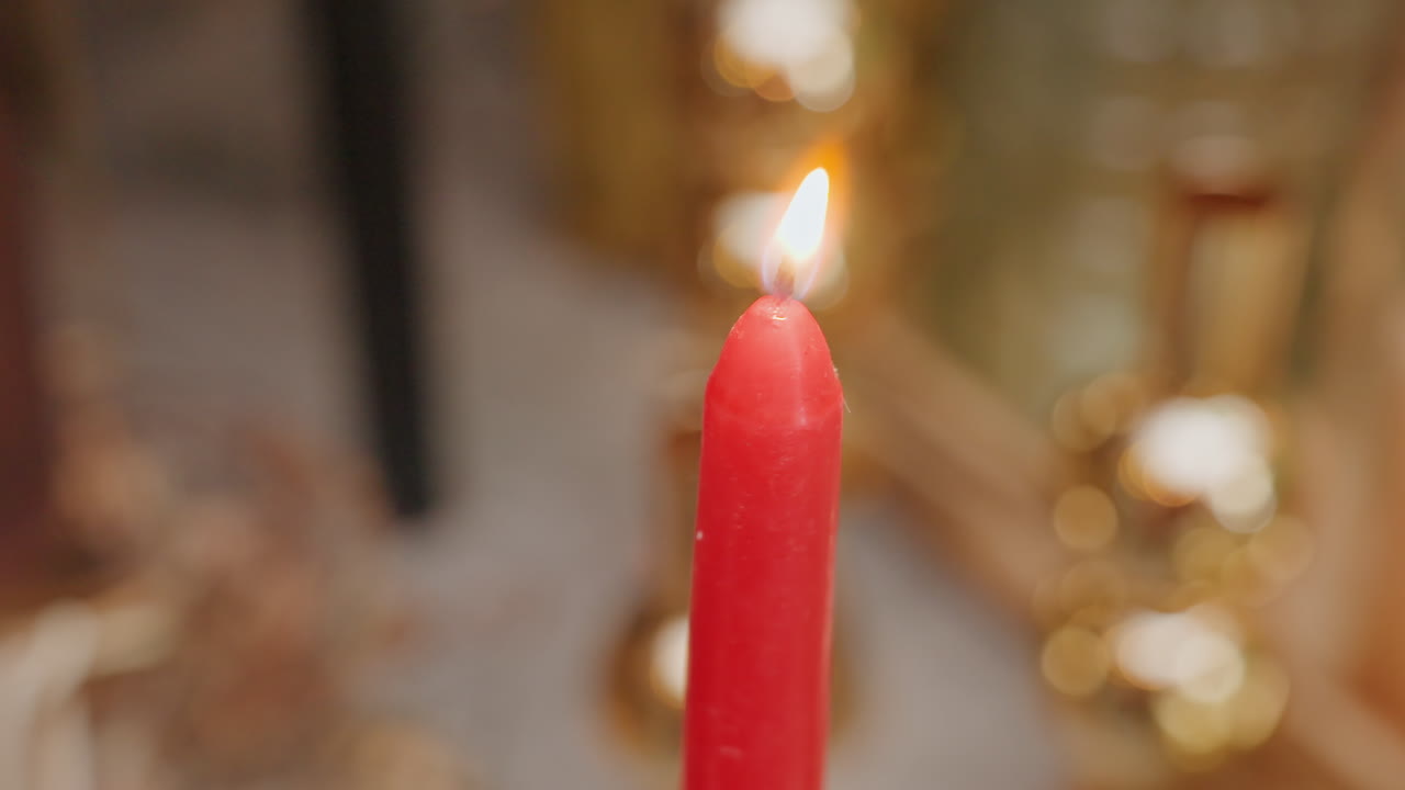Bagliore caldo in uno studio floreale. Fiamma tenue che proietta luce su un allestimento festivo dello spazio di lavoro di un fiorista. Primo piano di una candela accesa che crea un'atmosfera accogliente tra decorazioni floreali e accessori in ottone.
