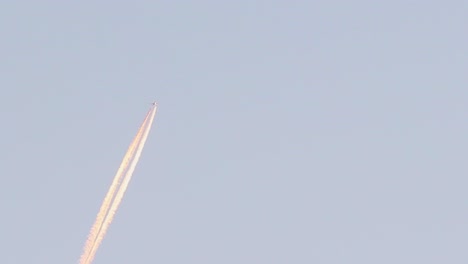 close view of jet reactor plane crossing the blue sky leaving a long white wake