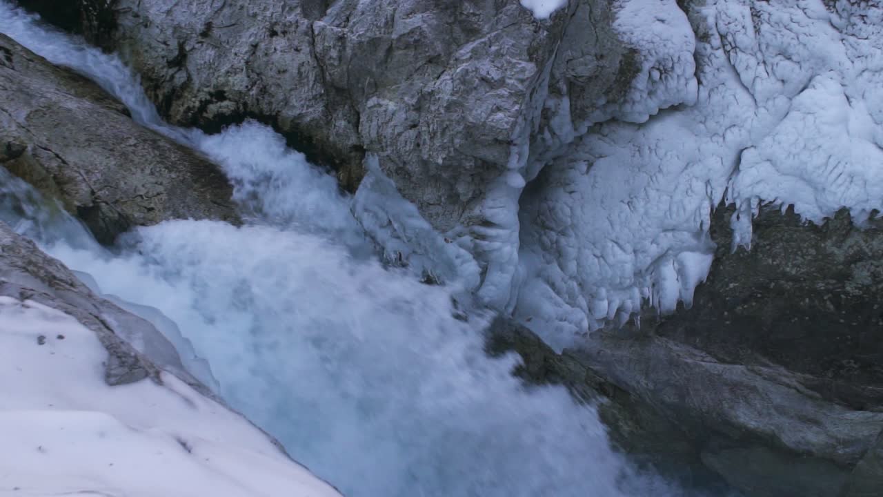 agua que cae desde acantilados de montaña entre montañas congeladas en invierno chapoteando en laderas rocosas