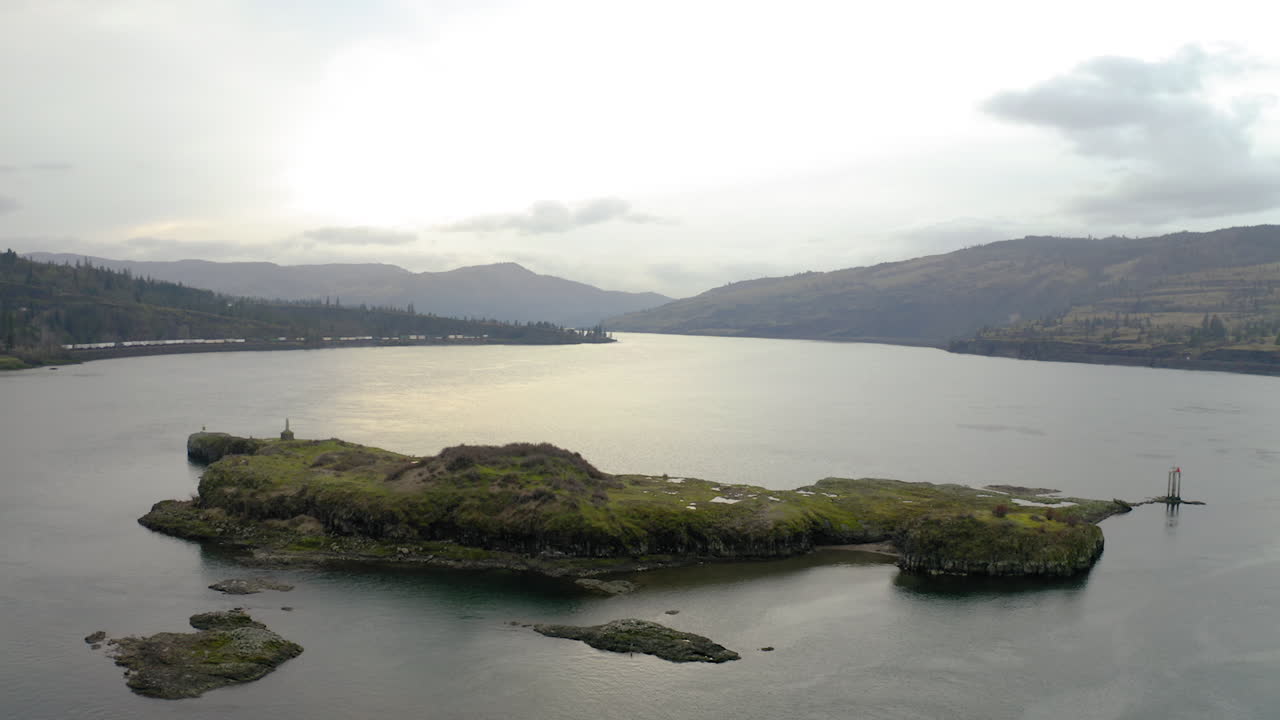 Overcast Landscape of a Wide River with an Island and Distant Mountains